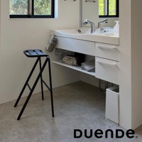 黑色金屬框架的吧檯椅，椅面為黑色皮革，椅腿呈A字型結構，椅面設計成可折疊的造型，適合放置於衛浴空間。