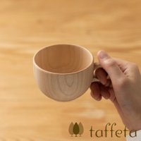 手持淺色楓木製茶杯，杯身圓潤，木紋清晰，搭配簡約木質背景。