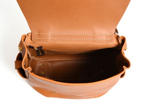 職人手作皮革屋瓦風經典雙扣後背包，採用天然棕褐色皮革，結構清晰，內裡空間寬敞，細節處以黃銅色五金件點綴。