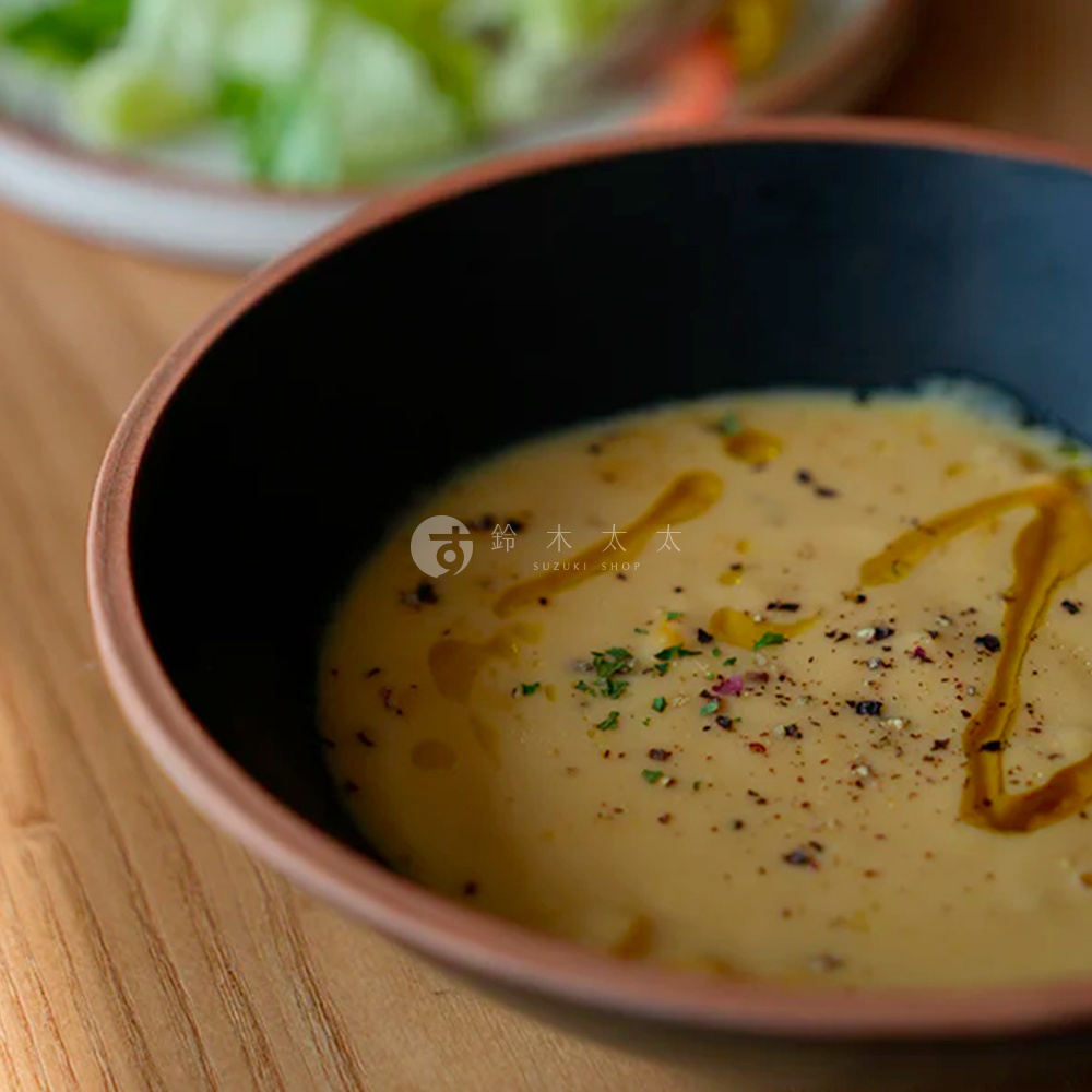 PURE 素燒百搭陶瓷沙拉碗，黑色內裡，外緣呈現陶土原色，碗中盛有濃湯，表面淋有橄欖油並撒有香料與黑胡椒。