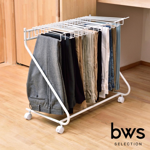 白色金屬製多功能落地移動褲架，帶有可容納多條褲子的水平掛桿，底部配有四個輪子，方便移動。褲架上掛有多條不同顏色和材質的褲子，包括灰色西裝褲、黑色褲子、卡其色褲子和牛仔褲。