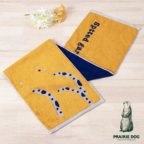 兩條黃色運動毛巾，其中一條印有藍色動物腳印刺繡圖案，另一條繡有藍色日文「spotted gar」。兩條毛巾均有深藍色和淺灰色滾邊。