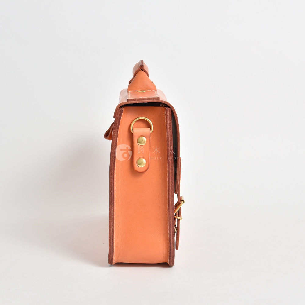 職人手作皮革經典三扣兩用商務公事包，側邊視角，展示淺棕色皮革材質，配有金色金屬扣環及調節皮帶。