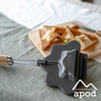 黑色金屬熱壓三明治烤夾，帶有木質手柄，烤夾上印有「apod」字樣，旁邊擺放著切成三角形的烤三明治。