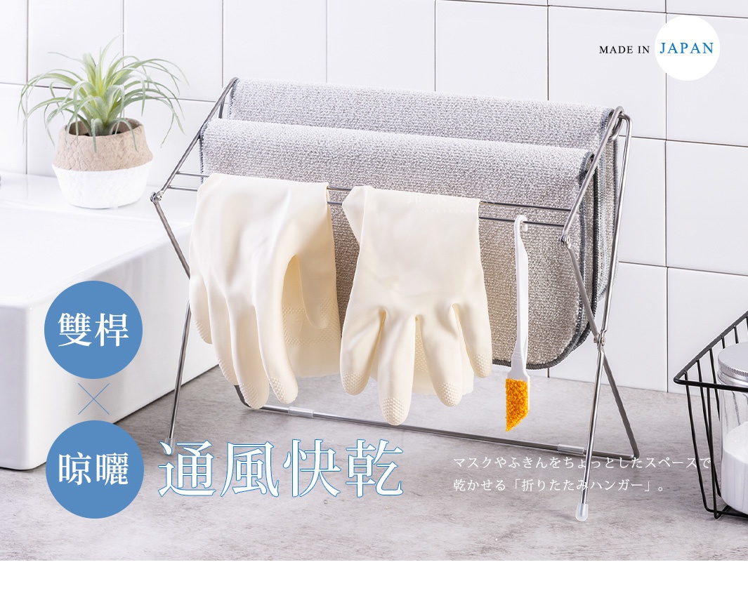 銀色金屬折疊式小物晾曬架，架上晾掛著一雙淺黃色橡膠手套、兩條灰色毛巾，以及一支白色柄橘色刷毛的清潔刷。