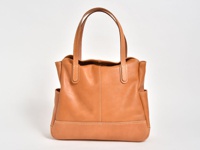 職人手作皮革直式肩背托特包，採用光滑淺棕色皮革製成，具有雙提把、外部側袋和縫線細節。