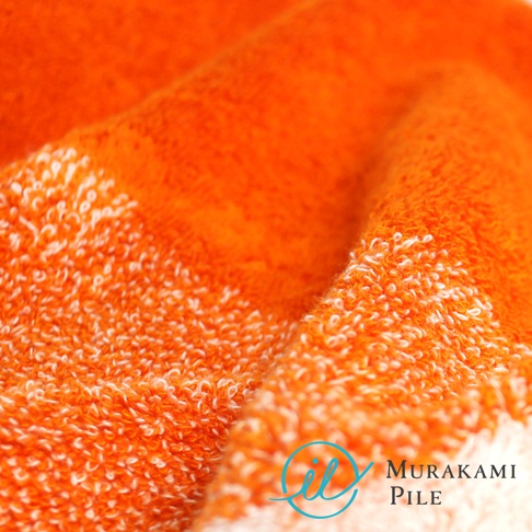 Murakami Pile 和一個藍色圓形圖標，背景是柔軟的橙色毛巾特寫