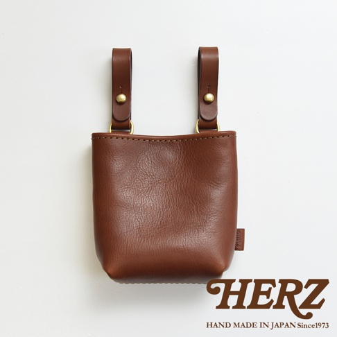 職人手作皮革多用途工作用腰袋 E-27，採用棕色皮革製作，設有兩個皮革掛帶和金屬扣環，可掛於腰間，方便工作使用。