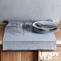 淺灰色條紋紋理的超細纖維吸水擦拭布，上面擺放著兩只透明玻璃杯、一疊淺藍色盤子和銀色餐具。