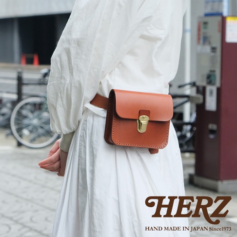 經典棕色皮革腰包，附有金色金屬鎖扣，由職人手工製作。