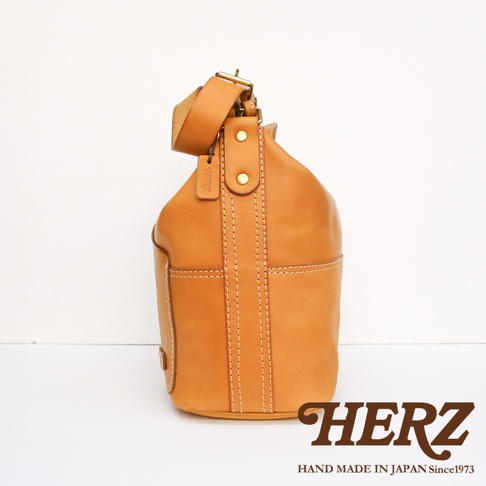 職人手作皮革厚實單肩波士頓包，天然棕色皮革，帶有明顯的縫線細節，可調節的肩帶，金屬扣件，以及品牌標誌。