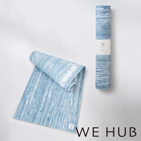 WE HUB 品牌標誌旁，兩個以藍白色調呈現、帶有木紋或水紋紋路的瑜珈墊，一個攤開，一個捲起，其中捲起的瑜珈墊上貼有產品標籤。