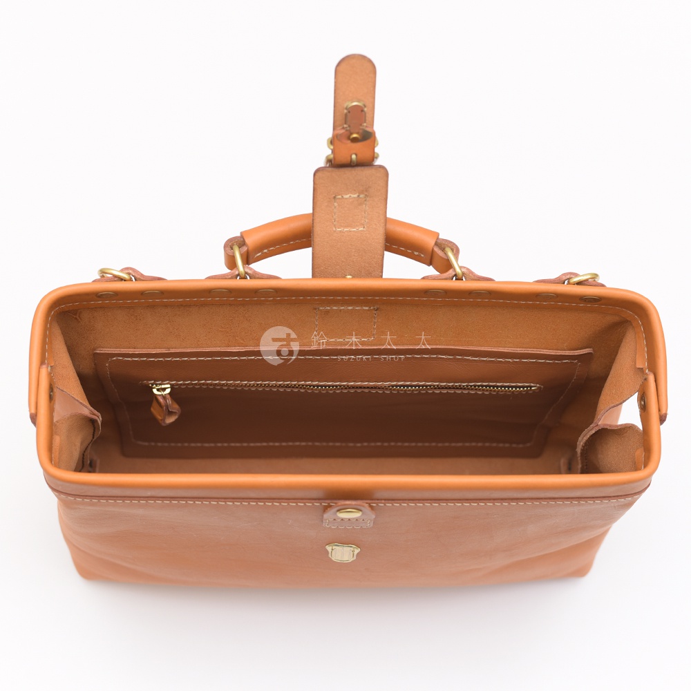 職人手作皮革軟式杜勒斯包，淺棕色皮革，頂部開啟，內有拉鍊內袋，金色釦件，白色縫線。