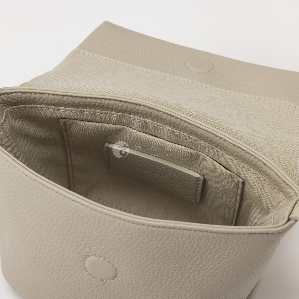 精緻紋理的淺灰色皮革迷你包內部，中間有品牌標誌和日文與英文文字。