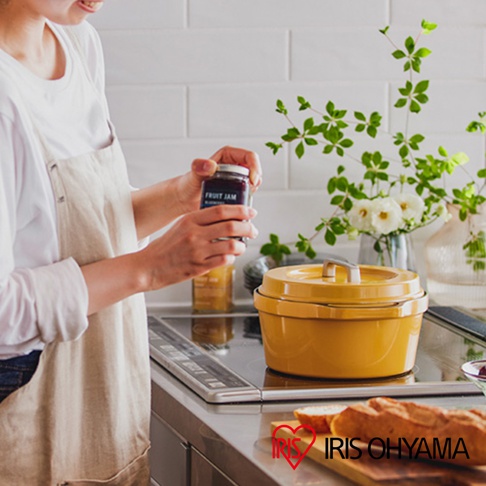 黃色 COCO 萬用無水調理鍋 24cm，帶有銀色提把，置於爐灶上，旁邊有一罐果醬和裝飾用花束。