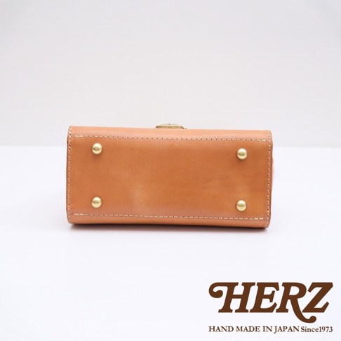 HERZ 職人手作，日本製造的駝色皮革包底部，帶有四個黃銅腳釘。