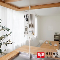 一個懸掛在天花板上的白色置物架，上面掛著廚房剪刀、夾子、削皮器和一個數位計時器，架子下方是一張木質桌面，桌面上有個金屬水槽。