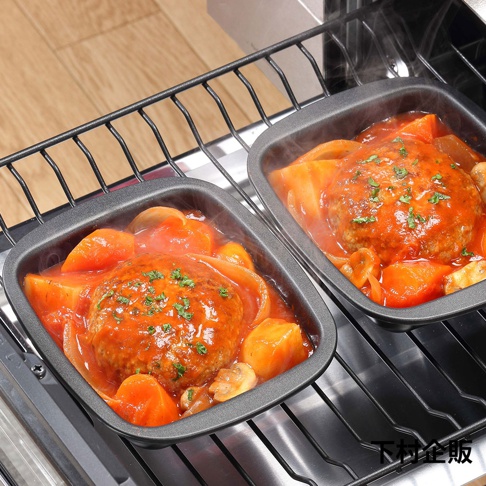 一組兩個深灰色迷你方形烤盤，內含燉煮的漢堡排、紅蘿蔔塊、洋蔥片和蘑菇，淋上紅醬，表面撒有蔥花，烤盤放置於烤箱烤架上，冒著熱氣。