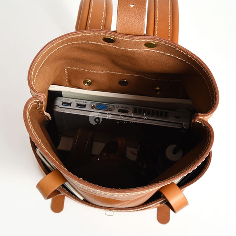 職人手作皮革雙口袋折蓋後背包，棕色皮革材質，內部空間展示，可放入筆記型電腦。