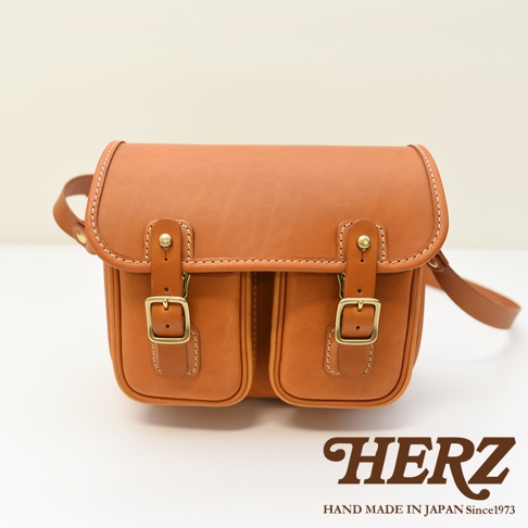 日本HERZ職人手作咖啡色皮革經典雙扣郵差包，配有兩個金色扣環和雙前袋，呈現復古風格。