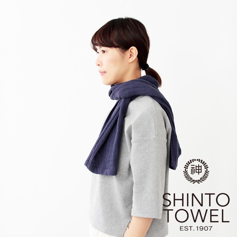 一位女士圍著深藍色2.5層紗浴巾，浴巾質地輕柔，呈現簡約風格。