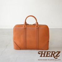 職人手作皮革Organ商務公事包 G-40，採用經典簡約設計，全皮製成，配有雙提把與金色拉鍊，呈現溫潤的焦糖棕色調。