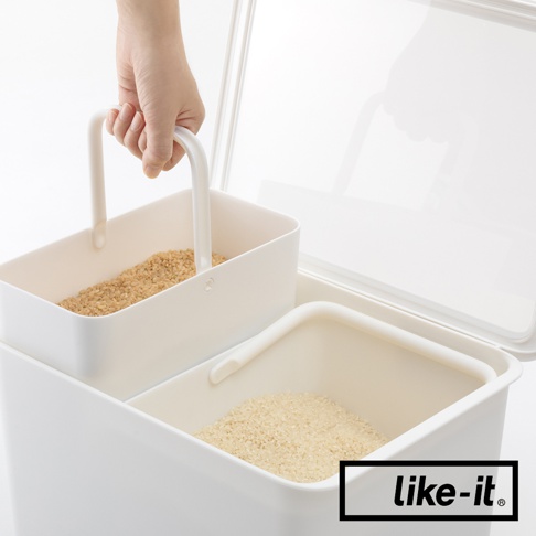 如同標題所示，圖片中的一個白色分隔收納盒，裡面裝有兩種不同種類的米。一個手正在從較小的、裝有深色米的分隔盒中取出。