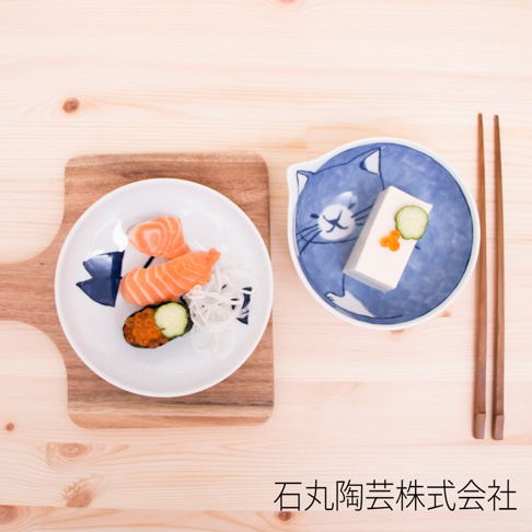 兩個陶瓷碗，一個裝有鮭魚壽司和蘿蔔絲，另一個裝有豆腐、小黃瓜片和鮭魚卵，碗的內側繪有藍色貓咪圖案，旁邊擺放著兩支木筷。