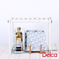 白色伸縮槽下單層站立收納架，上方有橫條紋設計，兩側有灰色旋鈕。架子下方放置一個白色線網收納籃，籃內有兩瓶醬料瓶，其中一瓶標有日文。收納籃旁有一個白色底、藍色北極熊圖案的方形盤子，盤子立在兩個木製架子上。