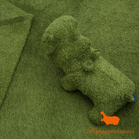 一隻綠色、竹棉混紡材質的可愛河馬造型抓握玩偶，放在同色系的毛巾布背景上，玩偶身體飽滿，有清晰的四肢和頭部輪廓，尾部有藍色與紅色的標籤。