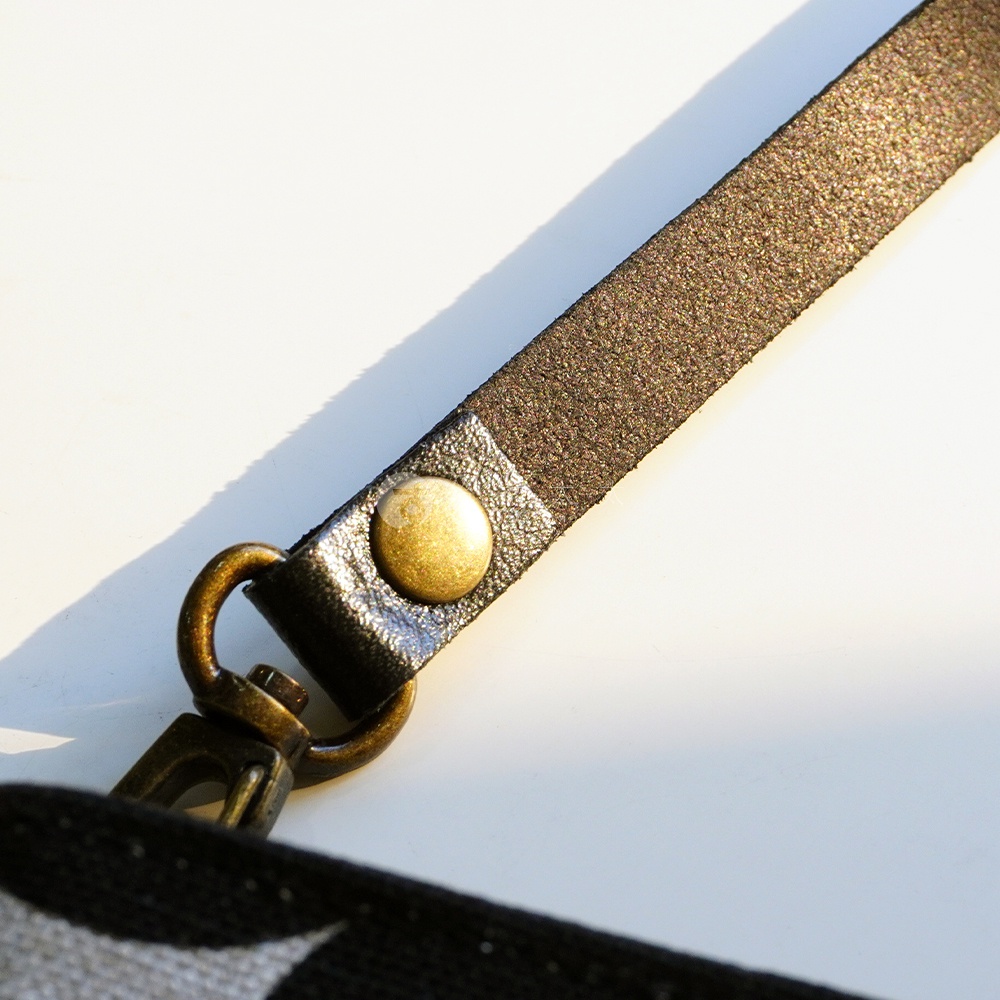 BAN INOUE 自然織紋麻布斜背包 (果實花紋) 的細節，展示了掛繩的金屬扣環和綴飾。