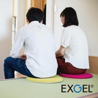 兩個人坐在黃色和粉紅色的圓形座墊上，座墊為單色，質地光滑，邊緣有灰色滾邊。