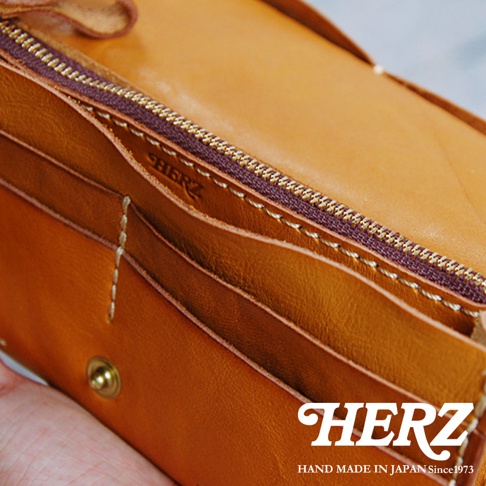 職人手作皮革軟皮長夾，焦糖色澤，質感柔軟，內部分層清晰，設有拉鍊及按扣，品牌標誌燙印於內側。