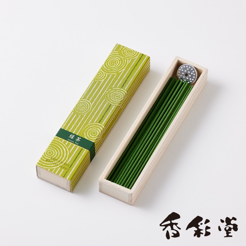 綠色紙盒裝著綠色線香，盒面印有白色螺旋紋和直線條。線香整齊排列在淺木色木盒中，盒內有一圓形金屬蓋。