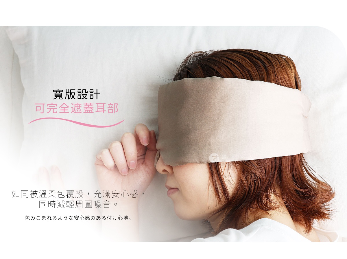 一位女性閉著眼睛側臥在白色枕頭上，佩戴著一款寬版設計的淺卡其色絲綢眼罩，該眼罩完整覆蓋了雙眼及耳朵，營造出溫柔包覆與減輕周圍噪音的放鬆睡眠氛圍，圖片左側附有描述寬版設計可完全遮蓋耳部及提供安心舒適感的文字說明。
