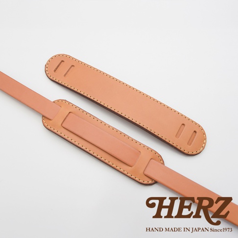 兩條職人手作皮革肩墊，淺棕色，帶有縫線細節，其中一條肩墊上有兩個長方形開孔。