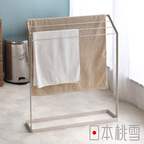 簡約風毛巾架上懸掛著一條白色和一條淺棕色毛巾，毛巾架為淺灰色金屬材質，呈現簡潔的線條設計，背景為淺色六角形地磚和窗簾。