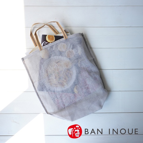 灰色網狀提把蔬果收納袋，袋內裝有雜誌、檸檬片及碗裝食物。