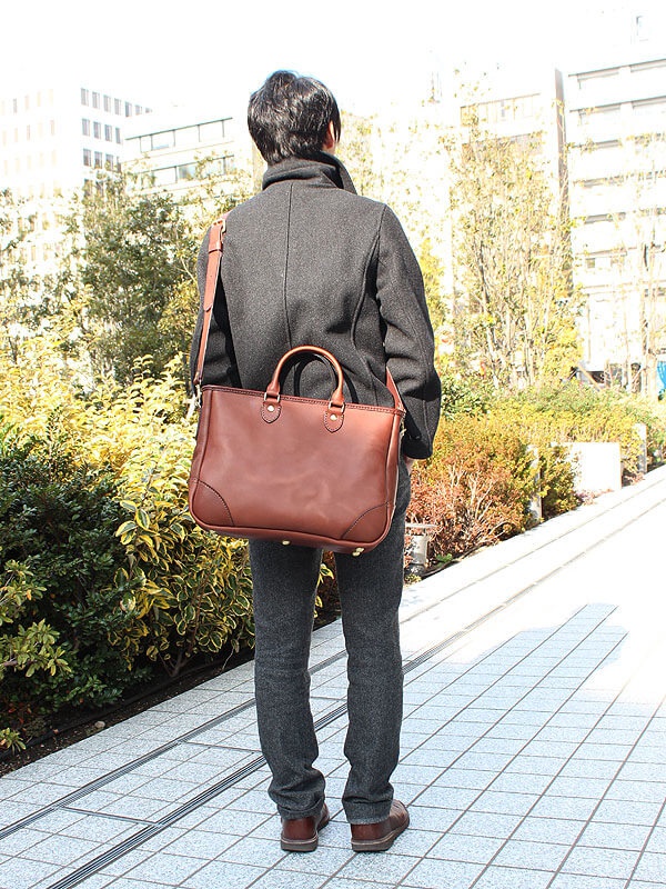 棕色皮革兩用商務托特包，配有可拆卸肩帶，包款設計簡約，適合商務場合。