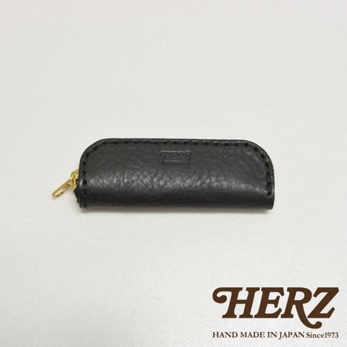 職人手作黑色皮革印章收納袋，採用壓紋皮革，配有金色拉鍊，袋身中央壓有品牌標誌。