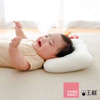 一名嬰兒躺在白色網狀材質的嬰兒皇冠枕上，嬰兒穿著淺褐色條紋上衣，面帶笑容。