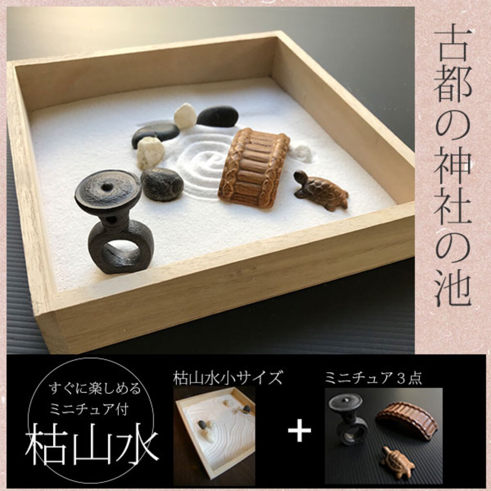 木製盒裝的日式枯山水模型，內含白色細砂、黑色與白色鵝卵石、一座棕色木紋橋樑裝飾、一隻褐色小烏龜模型，以及一個黑色圓形底座帶有兩個環狀結構的擺飾。