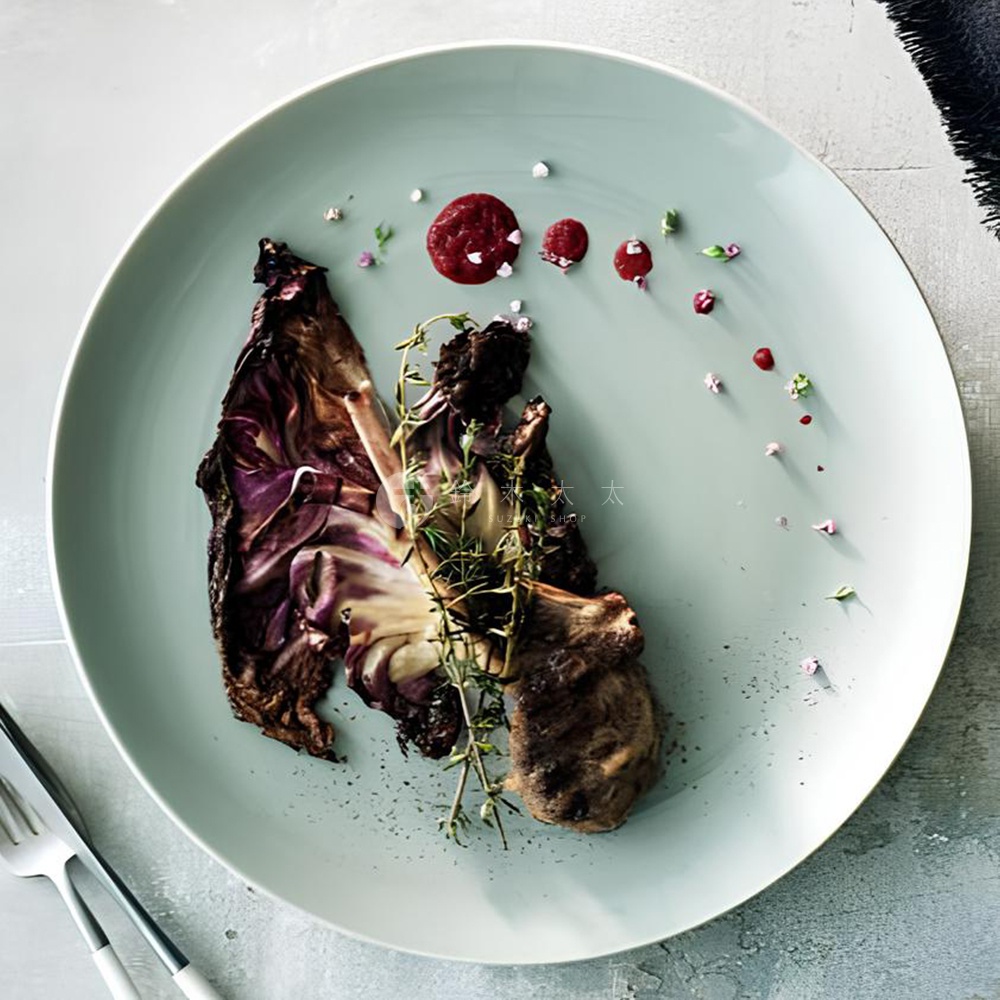 盤中擺放著烤紅蘿蔔搭配香草裝飾，點綴著少許紅色醬汁與細小的粉紅色花瓣。