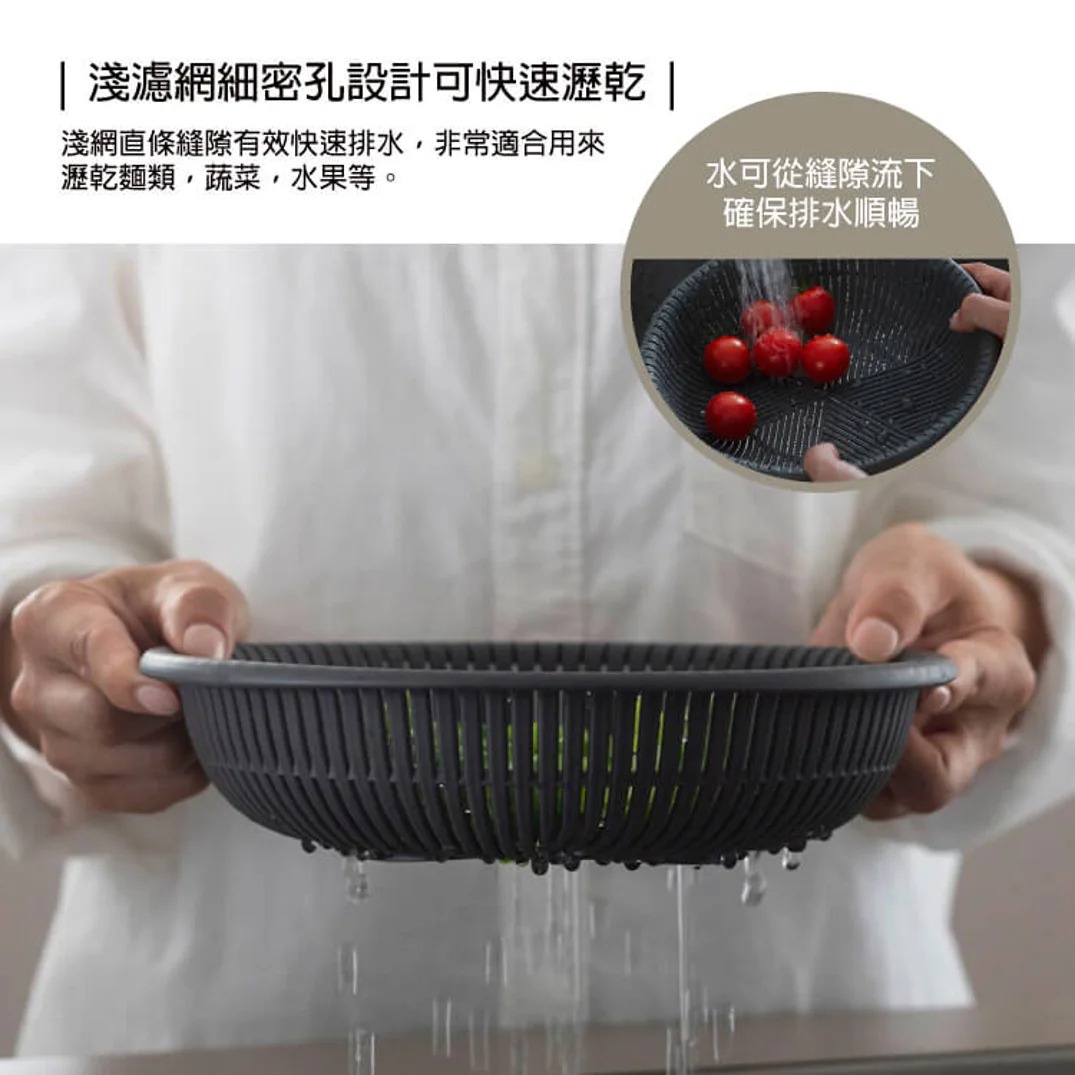 一個黑色濾水籃，裡面裝滿了綠色的蔬菜，籃子下方不斷有水滴落下，有助於快速瀝乾水分。