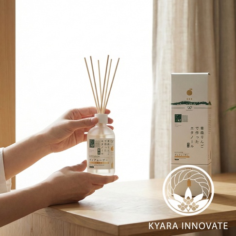 KYARA INNOVATE 青森蘋果香氛擴香竹，裝在透明瓶中，瓶身標有日文說明，瓶口插著多根擴香枝，背景為窗戶與布簾。
