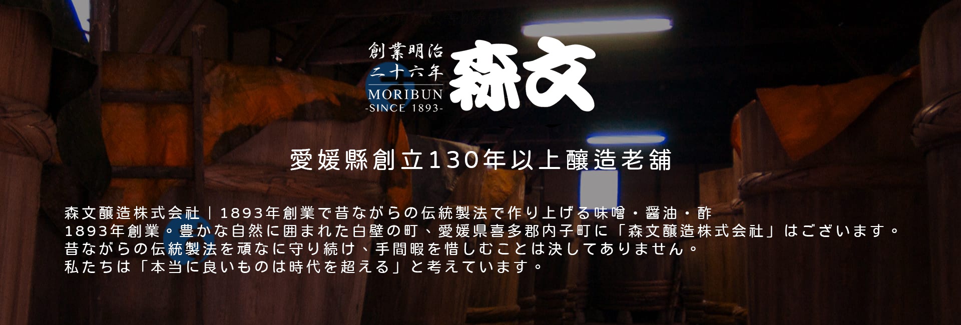 傳統木桶旁，擺放著日式醬油瓶，瓶身標籤為「秘藏醬油 500ml」，瓶蓋為紅色，背景為深色調，營造出古樸氛圍。