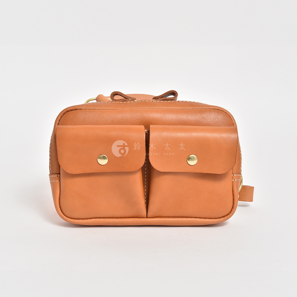 職人手作皮革雙口袋斜背包，淺棕色，設有兩個附有金色鈕扣的翻蓋前袋，整體為簡潔的方形設計，材質為皮革。