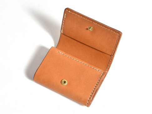 淺棕色皮革三折式迷你短夾，設有金色按扣，縫線精緻，風格簡約。
