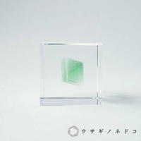 方形透明壓克力塊中，封存著一塊綠色的螢石礦石，呈現晶瑩剔透的質感。