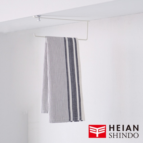 白色金屬製無痕櫥櫃捲紙架，懸掛於櫥櫃上方，下方掛有一條藍白條紋的布巾。